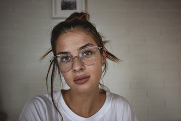 Close up portrait of young beautiful girl with reading glasses looking at the camera