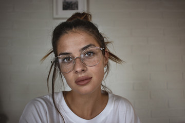 Fototapeta premium Close up portrait of young beautiful girl with reading glasses looking at the camera