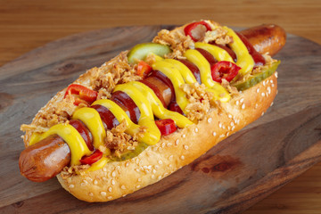 Hot dog with yellow mustard and ketchup on wooden board