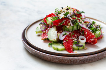  vegetable salad with tomato and cucumber, red onion, hot peppers, walnuts, a traditional Georgian dish, on a marble table