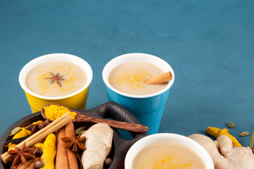 Indian Masala tea (Masala chai) or golden milk in multi-colored ceramic glasses next to the...