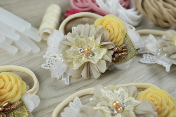 Fototapeta na wymiar A bouquet of flowers made out of fabric cloth textile in beautiful pastel colors placed on white wooden table that can be used as hair accessory, decoration, and embellishment