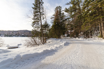 a road and a white scenery on the countryside next to a snow covered lake in winter