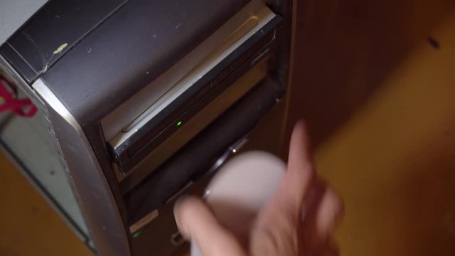 The human hand inserts and removes the CD disk from the old computer. CD rum, dusty azarpay system unit.