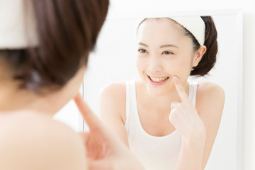 鏡で肌を見る女性