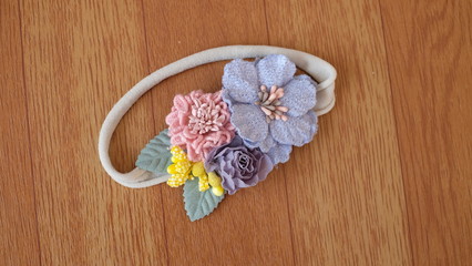 A bouquet of flowers made out of fabric cloth textile in beautiful soft blue, pink and gray colors placed on wooden table that can be used as hair accessory, decoration, and embellishment