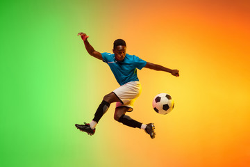 High jumping. Male soccer, football player training in action isolated on gradient studio...