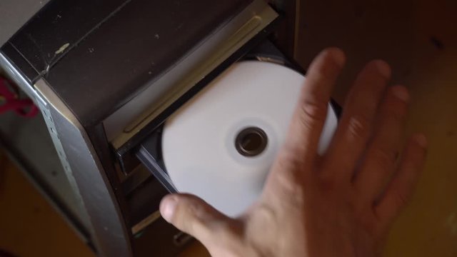The human hand inserts and removes the CD disk from the old computer. CD rum, dusty azarpay system unit.