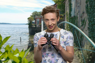 Teen boy using binoculars outdoor. Young curious boy holding binoculars on sea background. People,...