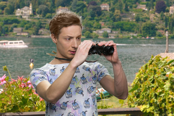 Teen boy observing sea with binoculars. Beautiful nature in the background. People, holidays and...