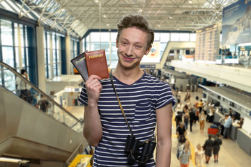 Portrait of cute tourist boy showing passports. Abstract blurred airport terminal interior background. Ready for travel.