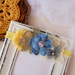 A bouquet of flowers made out of fabric cloth textile in beautiful soft pastel colors placed on wooden photo frame that can be used as hair accessory, decoration, and embellishment
