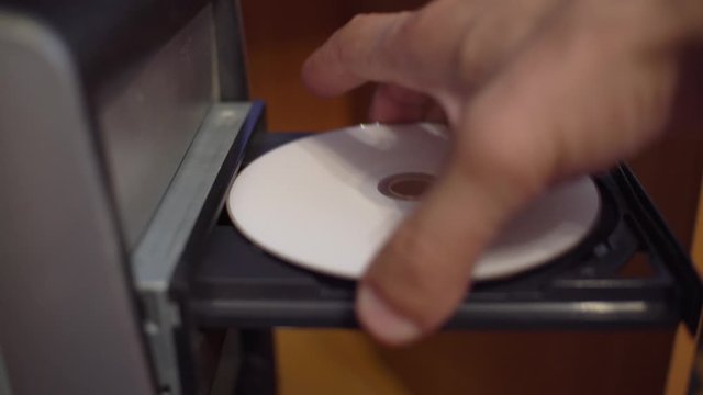 The human hand inserts and removes the CD disk from the old computer. CD rum, dusty azarpay system unit.