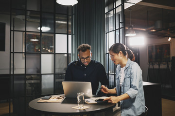 Smiling young businesspeople working on a laptop together
