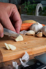 Peeling and cutting garlic on a wooden board. Man's hands.