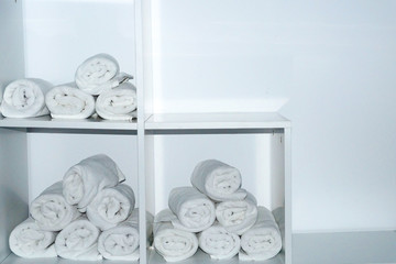 rolled white towels on white shelves close-up