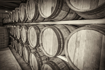 A row of traditional full whisky barrels, set down to mature, in a large warehouse facility