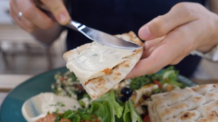 Hand spreading hummus on pita. Meze plates with salad, dips and pita. Healthy organic middle eastern cuisine. 