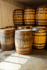 Old whisky barrels, stacked in a warehouse ready to fill with raw spirit and leave to mature over time, in a dusty warehouse