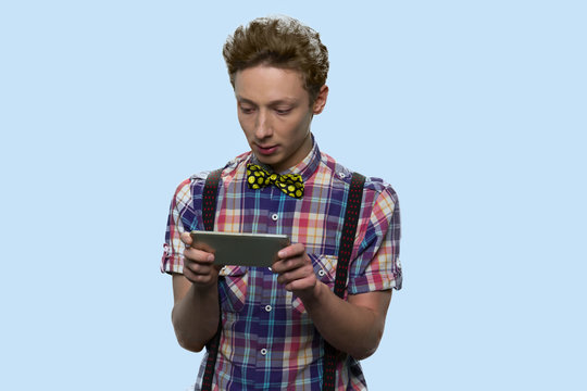 Smart teen boy playing game on smartphone. Concentrated teenage guy using smartphone on color background. Youth and modern technology concept.