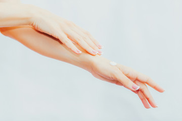 Naklejka premium Woman with french manicure applies cream to her hands