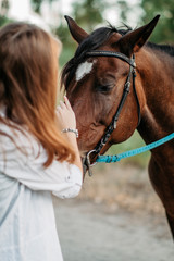 Fototapeta premium A little girl strokes a horse her favorite horse on the head. Communication of a child with a horse in the summer.