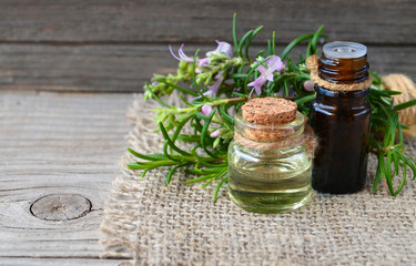 Rosemary essential oil in a glass bottles with fresh green rosemary herb on old wooden table for spa,aromatherapy and bodycare.Copy space.