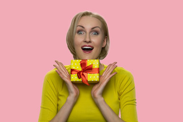 Happy expressive woman with gift box looking at camera. Portrait of shocked woman holding present...