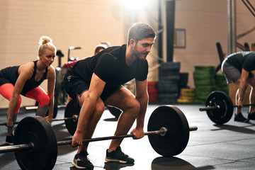 Obraz na płótnie Canvas Fit young man lifting weights during a gym class