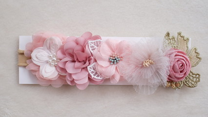 Handmade flower made out of fabric cloth textile in beautiful soft pastel pink theme colors placed on cardstock paper that can be used as hair accessory, decoration, and embellishment