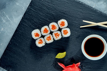 Appetizing maki sushi with salmon on a black slate board
