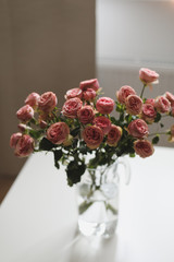 Pink roses flowers bouquet in glass vase against the window. Holiday celebration concept. Interior decoration