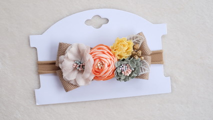 Handmade flower made out of fabric cloth textile in beautiful soft pastel colors placed on cardstock paper that can be used as hair accessory, decoration, and embellishment
