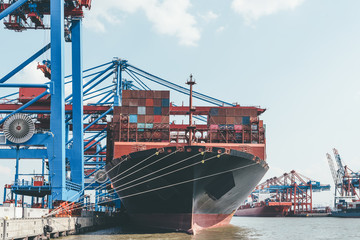 Naklejka premium large container ship under container gantry cranes in harbor, transport and trade concept