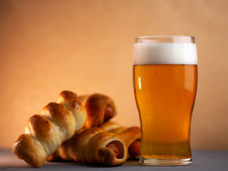A glass of lager and sausage rolls . Beer snack.