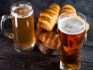 A glass of lager and sausage rolls . Beer snack.