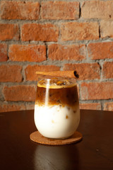 Ice coffee on a wood table with brick wall background.