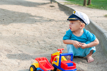 Child playing in the sand at a playground. Captain's hat.