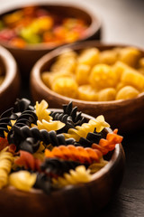 selective focus of colorful raw fusilli pasta in wooden bowl