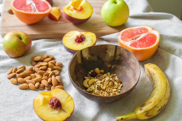 
Making a vegan smoothie bowl with peach, banana, chia, granola and almonds in a coconut bowl. Vegan breakfast.  Almond heart
