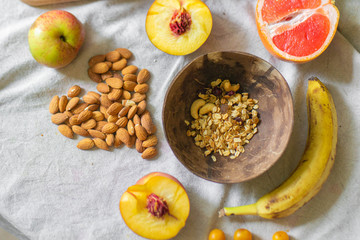 
Making a vegan smoothie bowl with peach, banana, chia, granola and almonds in a coconut bowl. Vegan breakfast.  Almond heart