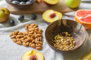
Making a vegan smoothie bowl with peach, banana, chia, granola and almonds in a coconut bowl. Vegan breakfast.  Almond heart