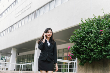 Beautiful asian business woman talking on cellphone while walking outdoor