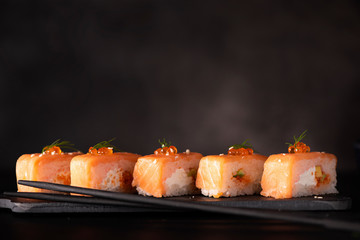 roll with salmon, cheese and avocado on black board