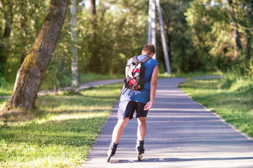Obraz premium A sporting man roller skating in park alley on summer day.