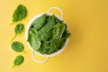 fresh spinach leaves in a white colander