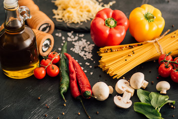 selective focus of raw Italian spaghetti with vegetables on black background