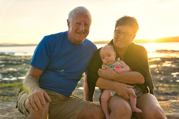 The grandparents playing with their baby granddaughter on the beach