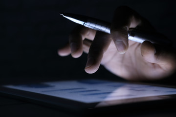 man's hand working on digital tablet at office desk, using self created chart 