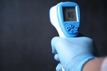 Hand holding infrared thermometer to measuring temperature.